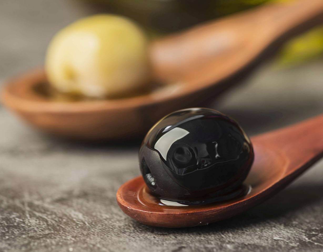 A black and green olive on spoons